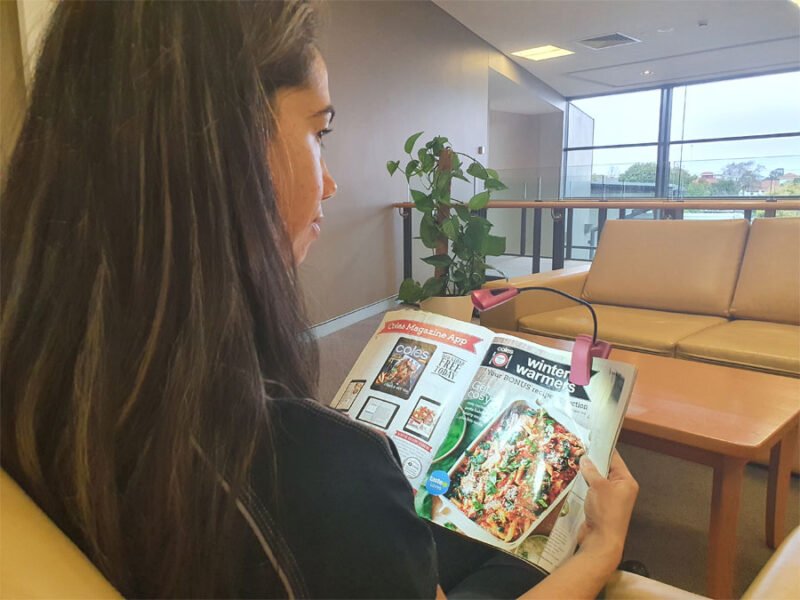 Occupational Therapist Keearny sits reading her magazine. A spotlight throws light onto the magazine page.